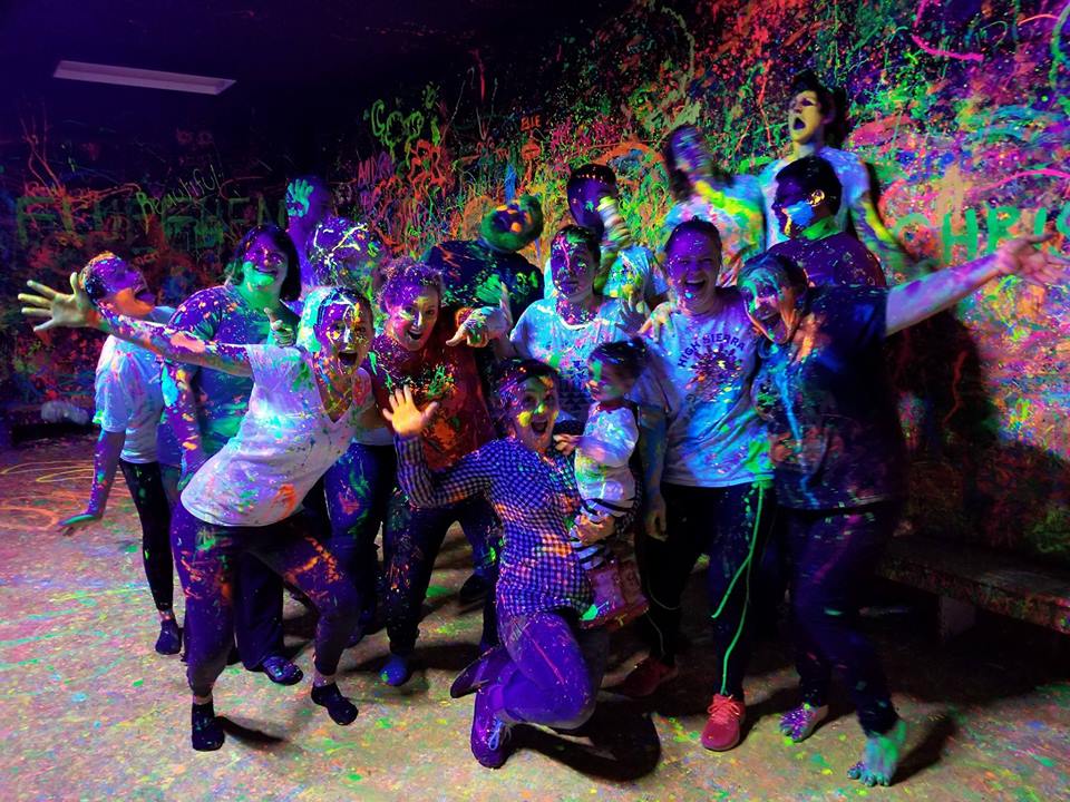 Photo of all age group covered in bright paint.