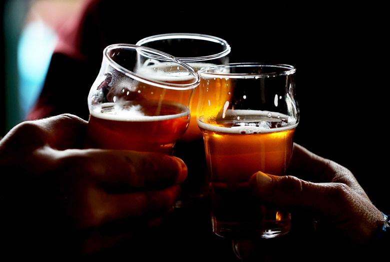 Photo of full beer glasses in peoples' hands.