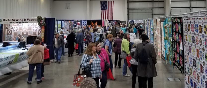 Photo of people viewing quilts at show.