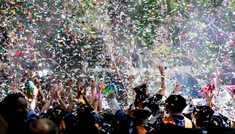 Photo of grads throwing hats and confetti