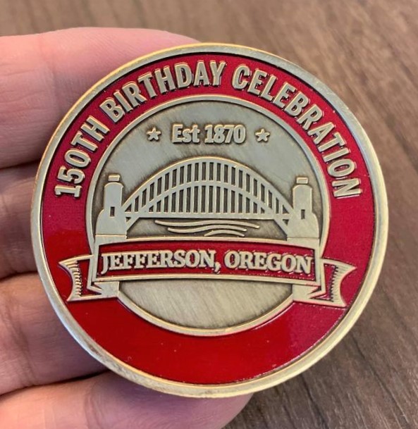 Photo of red and gold commemorative coin for Jefferson, Oregon 150th Birthday celebration.