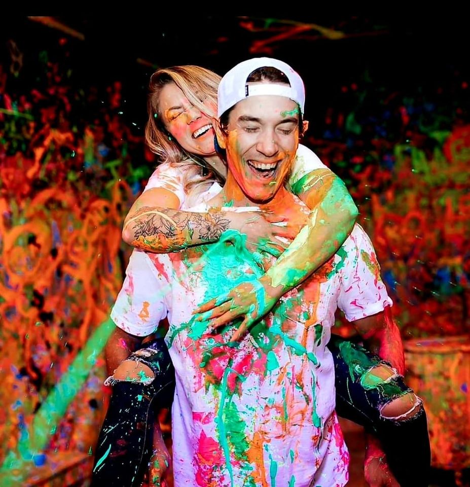 photo of woman and man covered in paint smiling