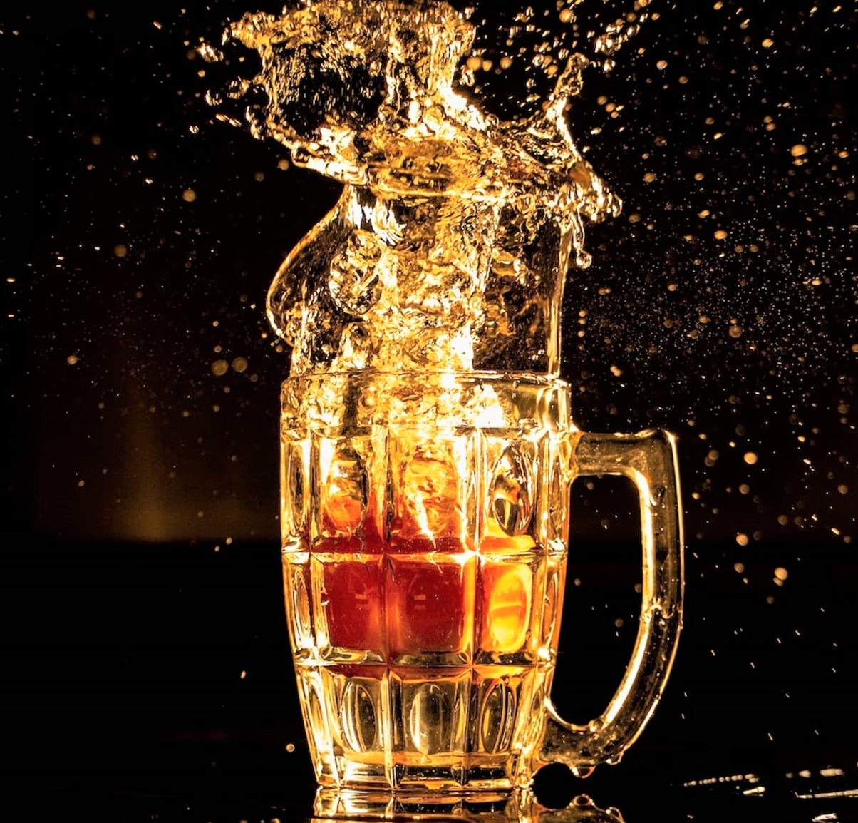 photo of beer splashing out of clear glass mug