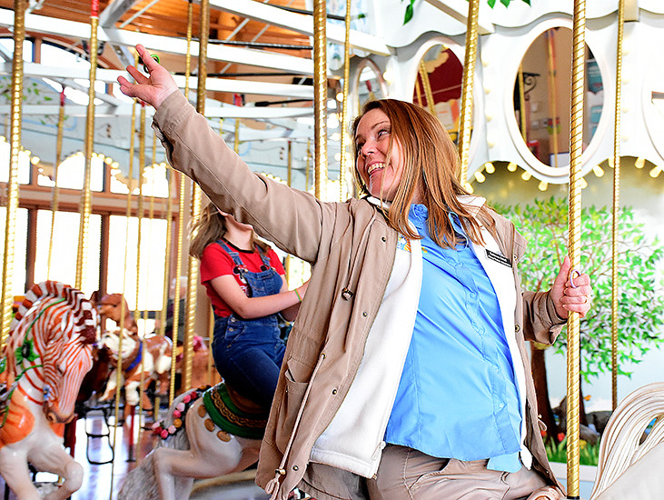 woman reaching for a ring at the Abany Carousel
