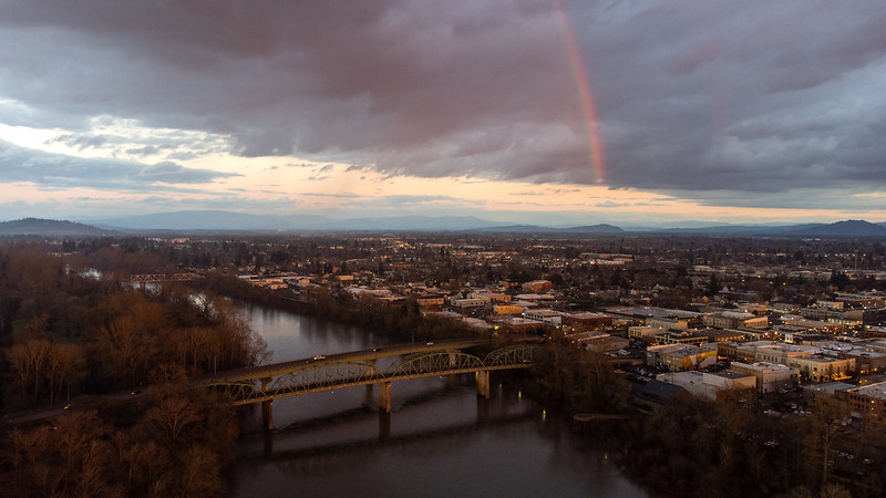 Ariel view of a bridge at dusk with clouds and a rainbow in the background